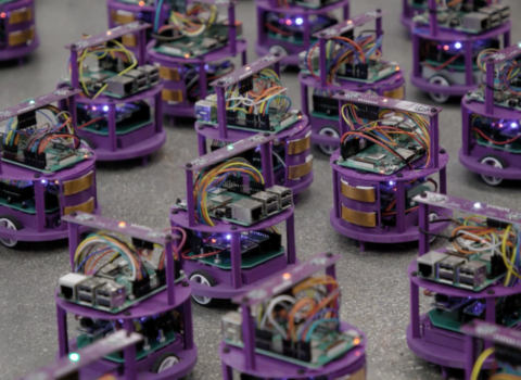 Small purple wheeled robots on the floor of a laboratory